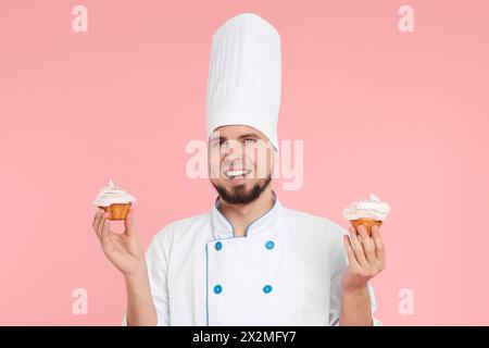 Dolcificante professionale in uniforme con deliziosi cupcake su sfondo rosa Foto Stock