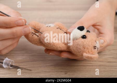 Donna che trattiene un simpatico orso giocattolo dalla lana al tavolo di legno, primo piano Foto Stock