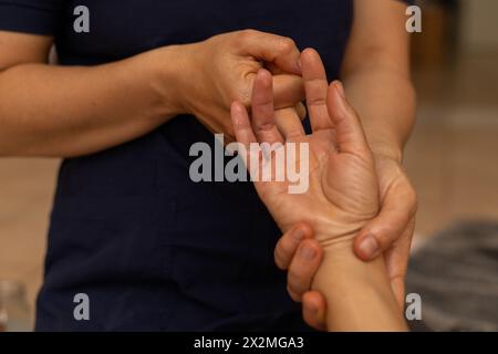 Donna latina sdraiata sulla schiena che riceve un massaggio ayurvedico in mano Foto Stock