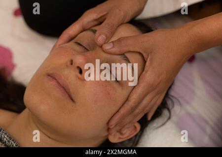 Donna latina che riceve un massaggio Shiroadhyanga sul viso con punti di pressione specifici Foto Stock