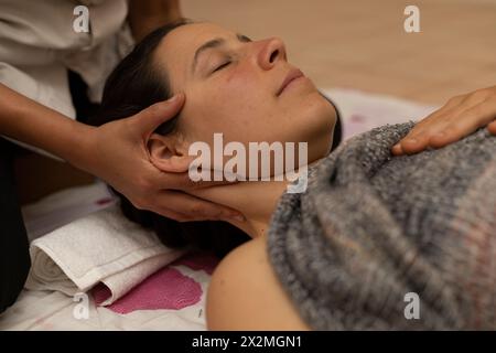 Donna latina che riceve un massaggio Shiroadhyanga sul viso con punti di pressione specifici Foto Stock