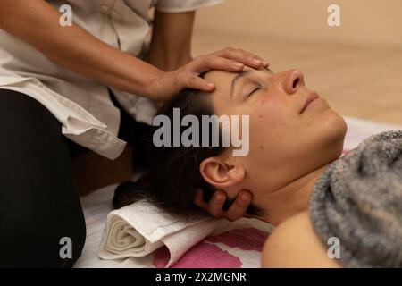 Donna latina che riceve un massaggio Shiroadhyanga sul viso con punti di pressione specifici Foto Stock