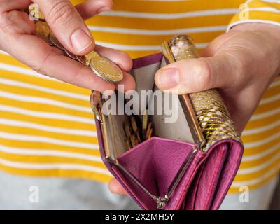 Primo piano di mani che mettono le monete britanniche in una borsa di denaro Foto Stock
