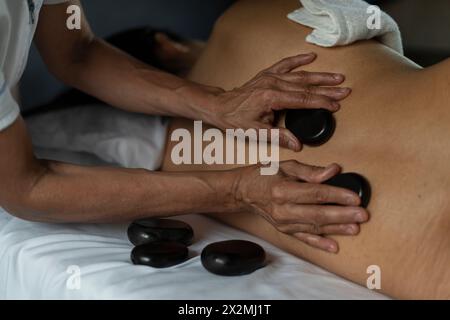 Primo piano di una donna incinta che riceve un massaggio schiena con pietre calde Foto Stock