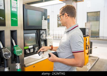 L'uomo paga il carburante con una carta di credito al terminal della stazione di servizio self-service in Europa Foto Stock