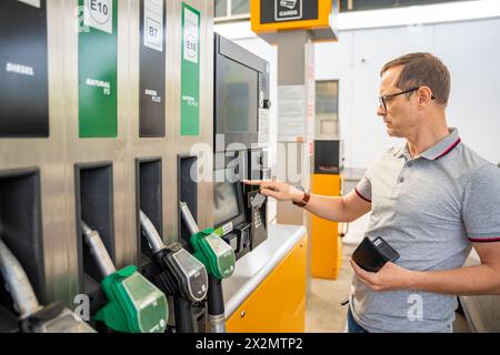 L'uomo paga il carburante con una carta di credito al terminal della stazione di servizio self-service in Europa Foto Stock