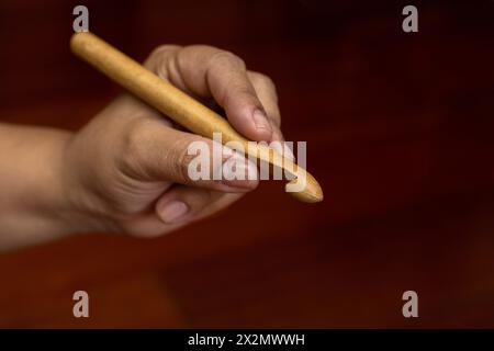 Primo piano delle mani di una donna che tiene un ago all'uncinetto di bambù. Concetto di svago e tempo libero Foto Stock