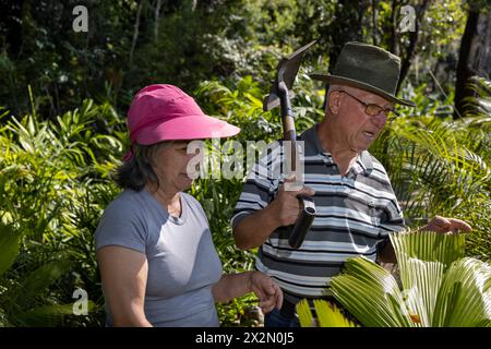 Due anziani dell'America Latina camminano attraverso il loro giardino sul retro, pensionati e concetto di tempo libero Foto Stock