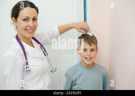 Medico misura crescita ragazzo in studio medico, concentrarsi su ragazzo Foto Stock