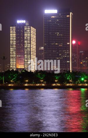 Alti edifici con illuminazione al neon vicino al fiume Pearl con riflessi di colore di notte a Guangzhou, Cina. Foto Stock