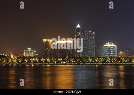 Costa con alti edifici con illuminazione al neon vicino al fiume Pearl di notte a Guangzhou, Cina Foto Stock