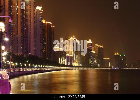 Alti edifici con illuminazione al neon sulla costa vicino al fiume Pearl con riflessi di colore di notte a Guangzhou, Cina Foto Stock