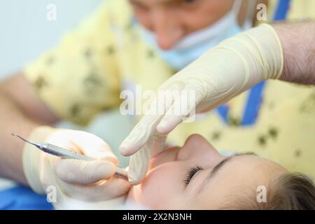 Dentista tratta i denti di ragazza in clinica dentale. Profondità di campo ridotta. Concentrarsi sul paziente. Foto Stock