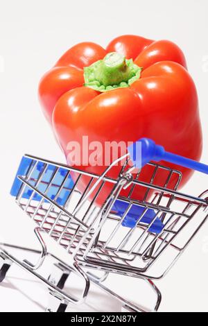 Grande e appetitoso peperone rosso nel carrello della spesa su sfondo bianco. Foto Stock