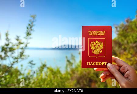 Uomo in possesso di passaporto russo sullo sfondo di un paese tropicale. Foto Stock