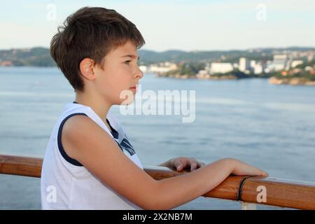 Un ragazzo premuroso sta a bordo della nave e guarda un bellissimo paesaggio Foto Stock