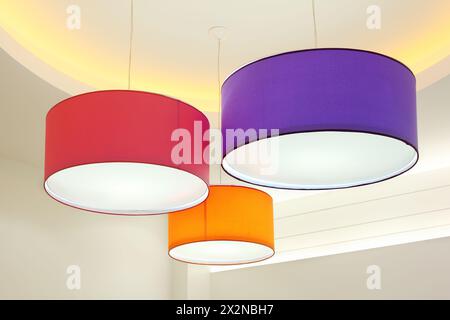 I paralumi rotondi viola, rosso e arancione sono appesi al soffitto Foto Stock