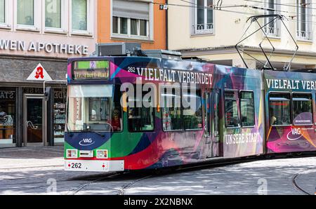Eine Strassenbahn der Linie 2 ist in den Strassen von Freiburg im Breisgau unterwegs. DAS tram trägt Werbung, dass die Vielfalt die Stadt verbindet. ( Foto Stock