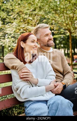 Un uomo e una donna godono di un momento di pace su una panchina nel parco. Foto Stock