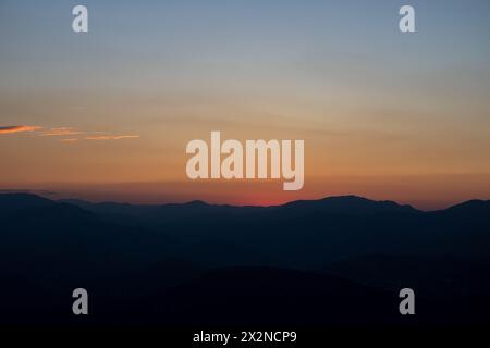 Profilo delle colline al tramonto con cielo nebbioso. Foto di sfondo al tramonto o all'alba. Foto Stock