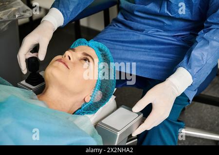 Una persona con scrub blu e guanti bianchi esegue la correzione della visione laser presso uno studio medico. Foto Stock