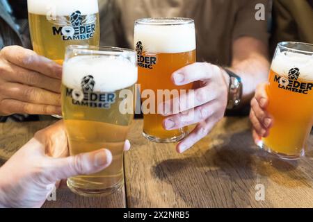 Le mani degli uomini tengono un bicchiere di birra Moeder Lambic, a Bruxelles, Belgio Foto Stock