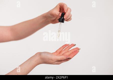 Bellissime mani da donna che reggono Un contagocce di olio e cura della pelle. Bellezza e salute. Cosmetici Foto Stock