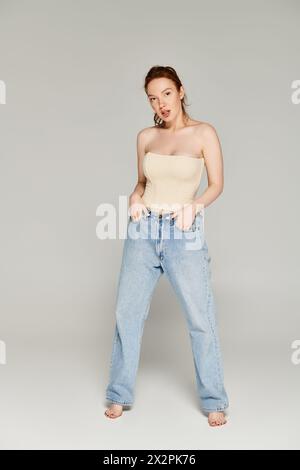 Una donna trasuda fiducia nei jeans e nella canotta, dando vita a una posa perfetta. Foto Stock