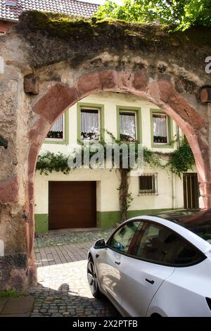 Weinheim, Germania - 19 maggio 2021: Auto sotto un arco di fronte a un edificio bianco e verde in una strada acciottolata a Weinheim, Germania. Foto Stock