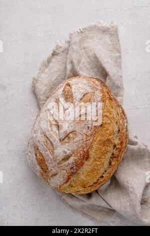 Pasta madre artigianale pane fatto in casa su tovagliolo di lino. sfondo grigio in cemento. Luce naturale con ombre tenui e vista ravvicinata Foto Stock