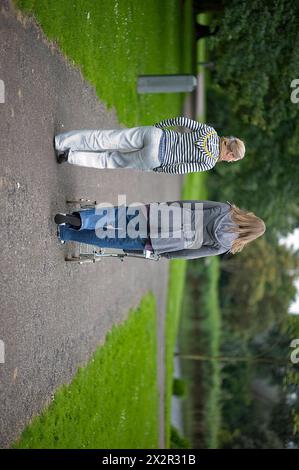 Due donne e un bambino due donne e un bambino all'interno di un puscart che parla e cammina alla Foresta di Kralingen durante un pomeriggio estivo. Rotterdam, Paesi Bassi. Rotterdam Vroesenpark Zuid-Holland Nederland Copyright: XGuidoxKoppesxPhotox Foto Stock