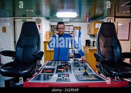 Capitano sul ponte capitano sul ponte della nave portacontainer MS Flintercape, utilizzando un binocolo, durante un viaggio dal porto di Rotterdam verso Sundsvall, Svezia. MRYES Rotterdam NLD - Sundsvall se Containervessel MS Flintercape Noordzee, Baltische Zee, Golf va Paesi Bassi Copyright: XGuidoxKoppesxPhotox Foto Stock