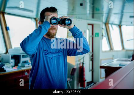 Capitano sul ponte capitano sul ponte della nave portacontainer MS Flintercape, utilizzando un binocolo, durante un viaggio dal porto di Rotterdam verso Sundsvall, Svezia. MRYES Rotterdam NLD - Sundsvall se Containervessel MS Flintercape Noordzee, Baltische Zee, Golf va Paesi Bassi Copyright: XGuidoxKoppesxPhotox Foto Stock