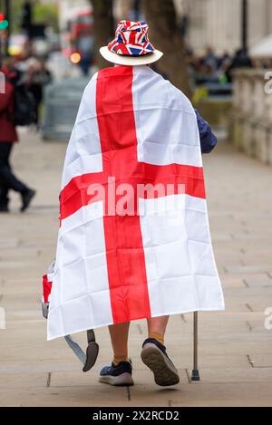 Londra, Regno Unito. 23 aprile 2024. Un uomo che indossa una bandiera inglese e un cappello Union Jack cammina lungo Whitehall il giorno di San Giorgio. Crediti: Mark Thomas/Alamy Live News Foto Stock