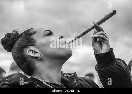 Immagine in bianco e nero di una giovane donna che sta trascinando un grande giunto di cannabis durante l'evento 420 a Londra. Foto Stock
