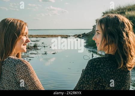 Figlia sorridente che passa il tempo libero con la madre via mare Foto Stock