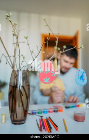 Uova di Pasqua appese su ramoscelli con padre e figlio sullo sfondo Foto Stock