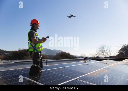 Tecnico maturo drone volante in piedi accanto al pannello solare Foto Stock
