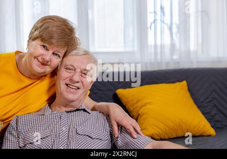 Una coppia anziana sorridente seduta a casa Foto Stock
