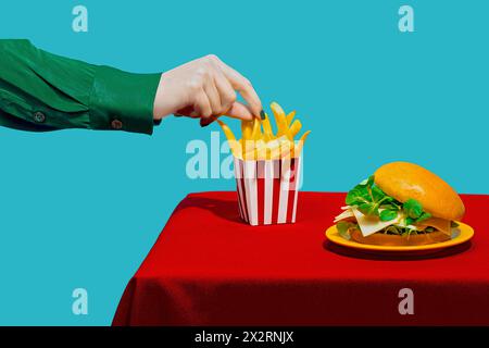 Mano di donna che raccoglie patatine fritte dal tavolo su sfondo blu Foto Stock