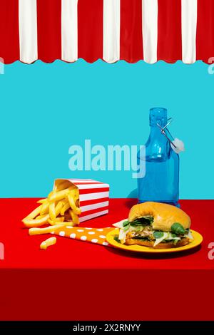 Hamburger di pollo con patatine fritte vicino alla bottiglia di bibita sul tavolo su sfondo blu Foto Stock