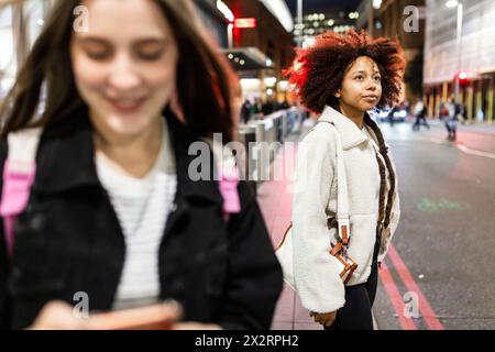 Giovane donna premurosa in piedi vicino ad un amico per strada Foto Stock
