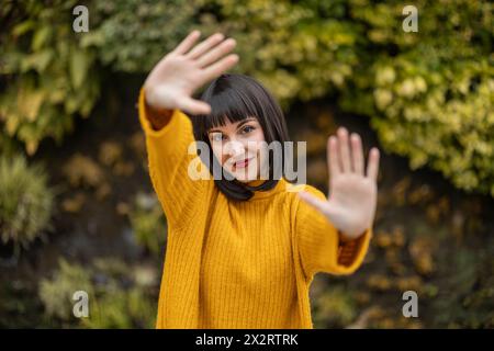 Donna sorridente con le scosse che fanno un gesto di stop Foto Stock