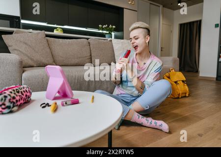 Giovane donna che tiene con sé un pennello e canta nel salotto di casa Foto Stock