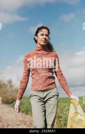 Donna che tiene bottiglie in un sacchetto di plastica in campagna Foto Stock