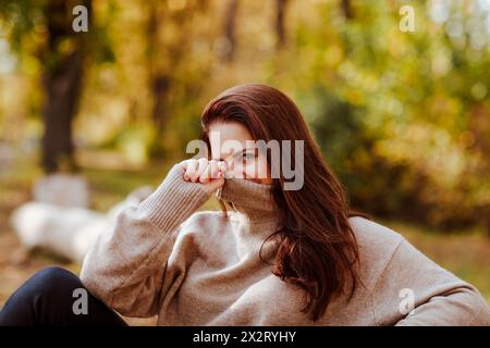 Donna matura che ricopre il viso con una t-shirt dolcevita nel parco Foto Stock