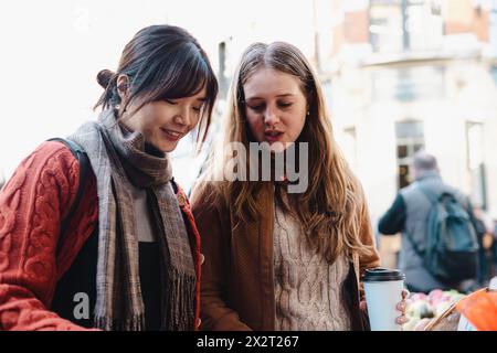 Sorelle che indossano abiti caldi e parlano al mercato Foto Stock