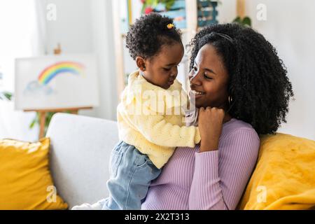 Felice madre single che gioca divertendosi con la figlia nel soggiorno di casa Foto Stock
