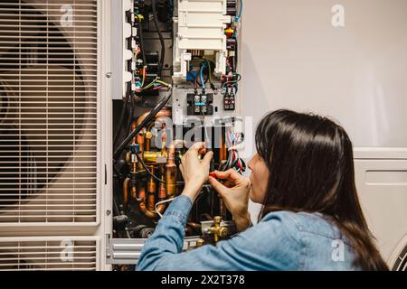 Tecnico donna che esamina l'unità CA Foto Stock