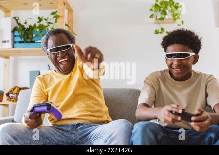 Allegri nonno e nipote che giocano a videogame a casa Foto Stock